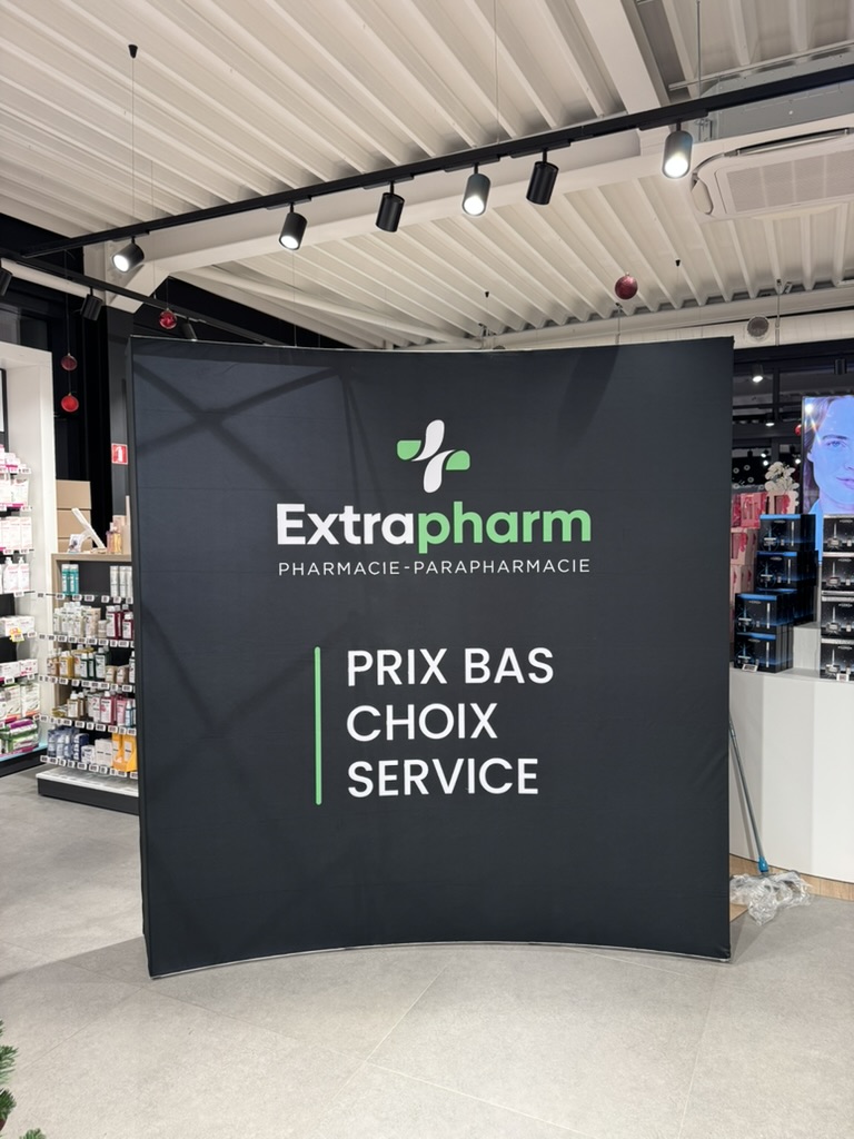 Stand Extrapharm au fond textile noir incurvé « Prix bas, choix, service », installé dans un point de vente.