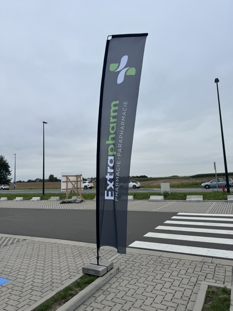 Oriflamme Extrapharm installée sur un parking extérieur, près d'un passage piéton.
